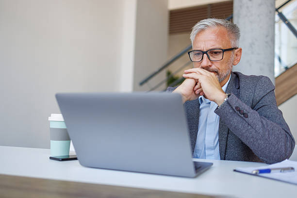 istock Thoughtful senior man working on laptop in modern office 2241391519