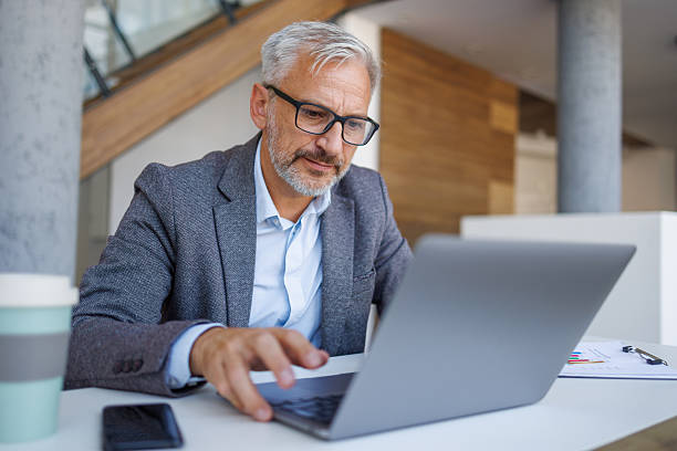 istock Mature businessman working on laptop in modern office 2241391553