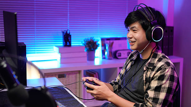 istock Attractive Asian male gamer enjoys playing online games on his computer feeling happy while live streaming a cyber tournament from home 2241393901