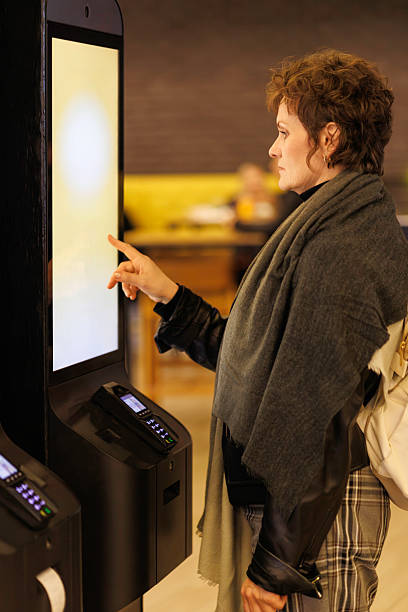 istock Woman using a self-service restaurant kiosk to place an order at a modern cafe 2241394589