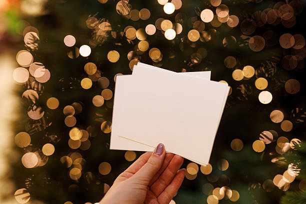 istock Hand holding blank postcard in front of Christmas lights 2241395919
