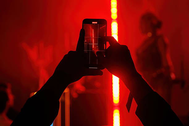 istock Hands filming red-lit concert on smartphone at night 2241395965