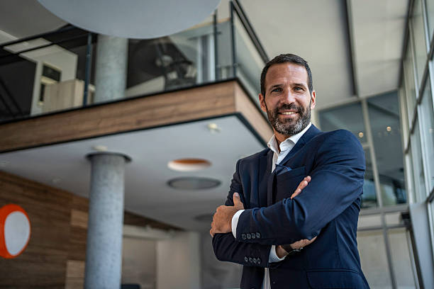 istock Confident businessman standing in modern corporate office smiling 2241395979
