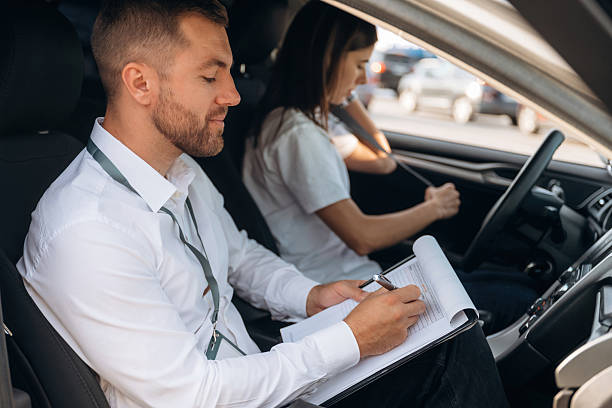 istock Side view. Woman is with instructor in car, driving school concept 2241396710