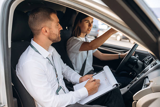 istock Side view. Woman is with instructor in car, driving school concept 2241396780