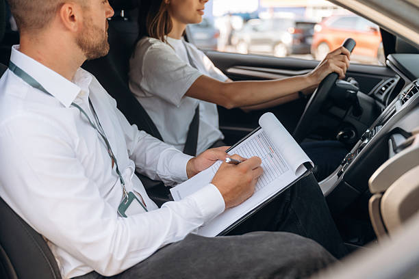 istock Data is being written into the notepad. Woman is with instructor in car, driving school concept 2241396787