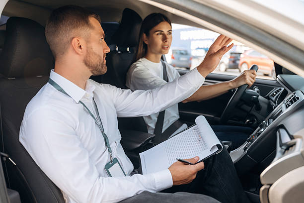 istock Data is being written into the notepad. Woman is with instructor in car, driving school concept 2241396806