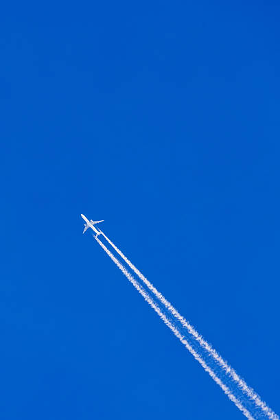 istock Aeroplane flying on a clear blue sky with white vapor trails 2241398464