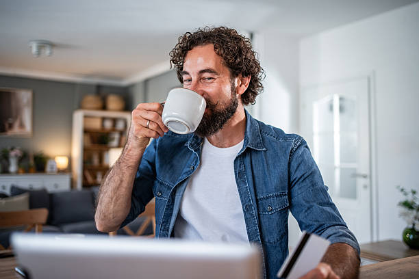 istock Man drinking coffee online shopping at home 2241399048