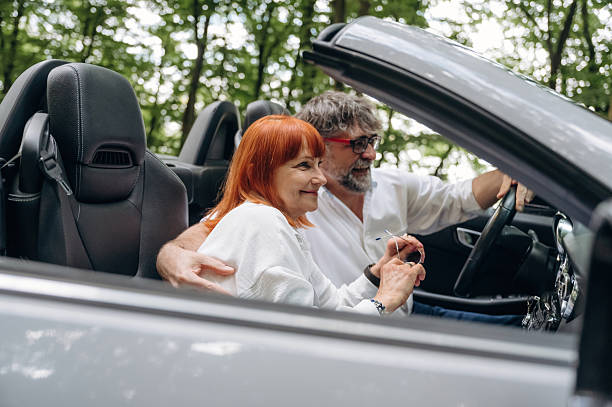 istock View from the side. Senior couple driving convertible cabriolet car 2241401099
