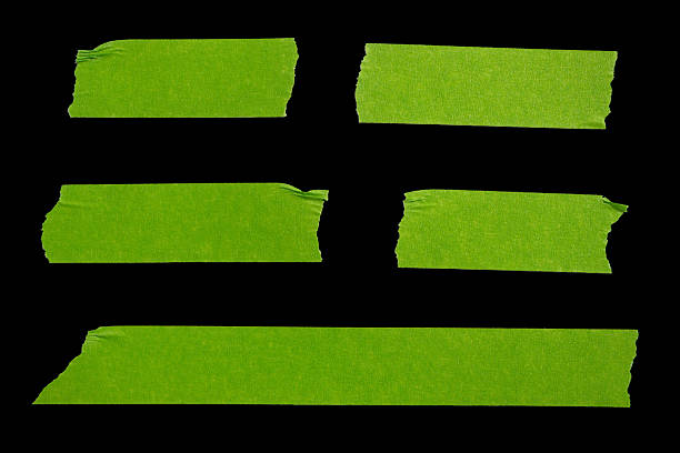 Green adhesive torn paper masking tape pieces isolated on black background