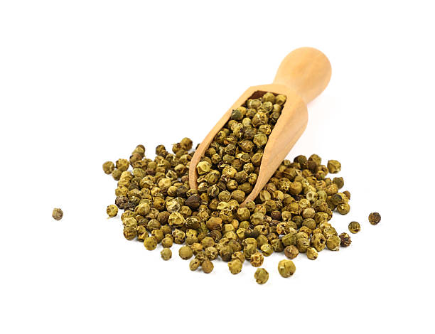 istock Green peppercorns with a wooden scoop on white background 2241402216