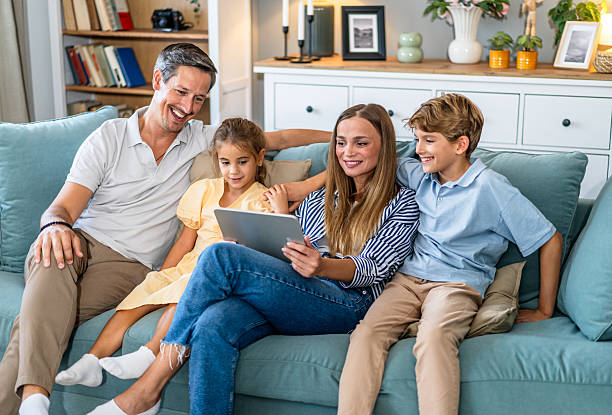 istock Family relaxing on couch together using digital tablet 2241402337