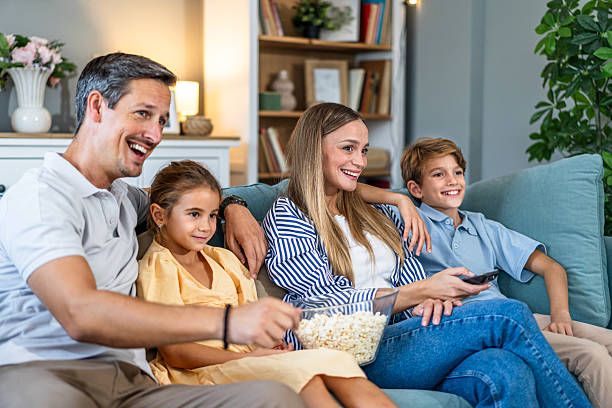 istock Family relaxing on couch watching tv together 2241402426