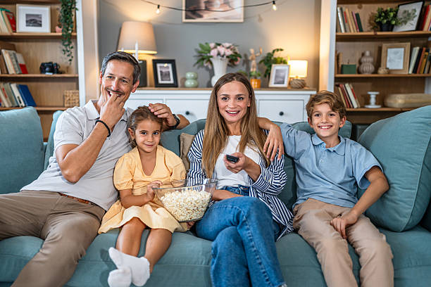 istock Family relaxing on couch watching tv with popcorn 2241402470
