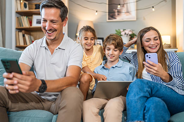 istock Family relaxing on sofa using smartphones and tablet 2241402664