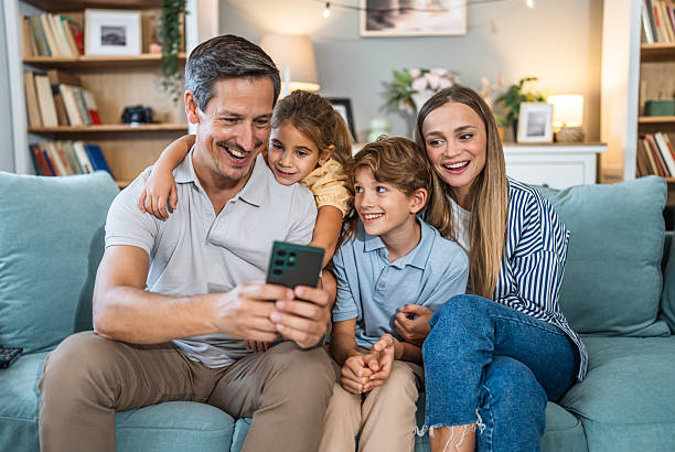 istock Family watching smartphone together on sofa at home 2241403082
