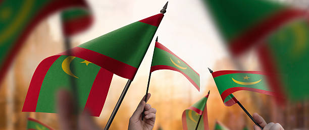 istock Mauritania flags in their hands on a blurred urban background 2241404010