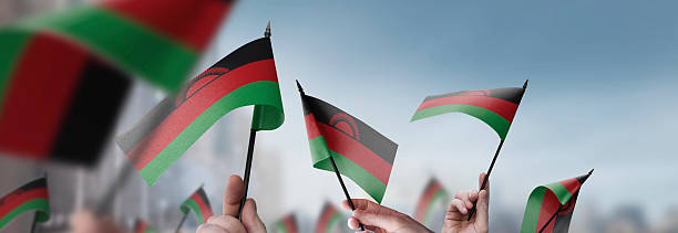 istock Malawi flags in their hands on a blurred urban background 2241404119