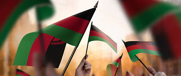 istock Malawi flags in their hands on a blurred urban background 2241404145