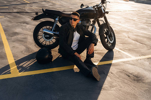 istock Sitting on the ground. Man is outdoors with his motorcycle 2241406086