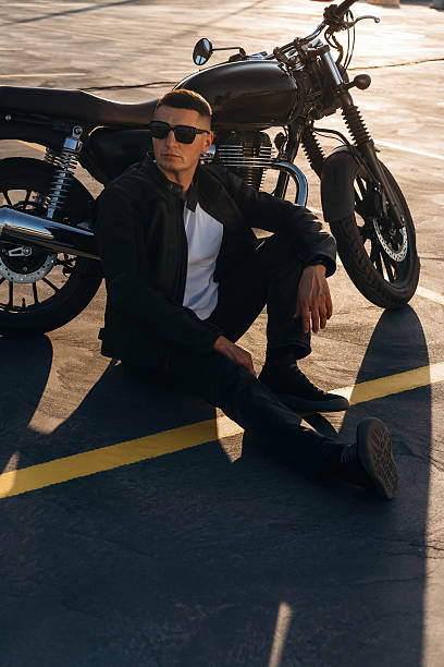 istock Sitting on the ground. Man is outdoors with his motorcycle 2241406088