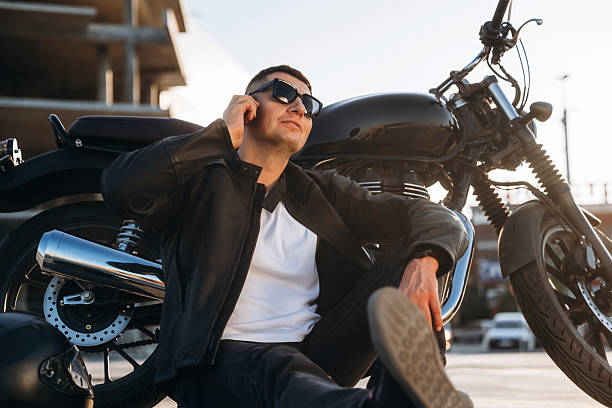 istock Having conversation by the phone. Man is outdoors with his motorcycle 2241406147