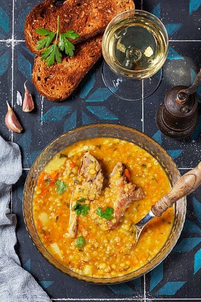 istock Lentil soup with pork and vegetables, served with white wine and croutons. 2241407821