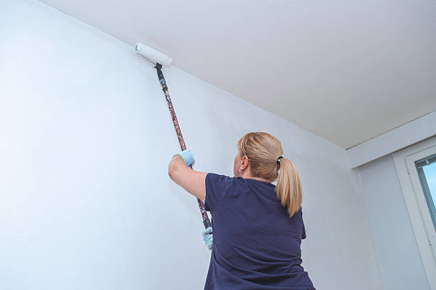 istock A Caucasian woman, a painter, paints a wall with a paint roller, with white paint. 2241408312