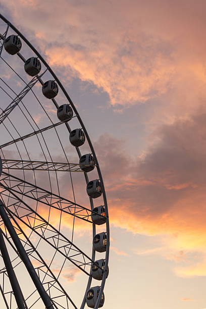 istock large Ferris wheel against a cloudy sky. The Ferris wheel is surrounded by sunset clouds. 2241410746