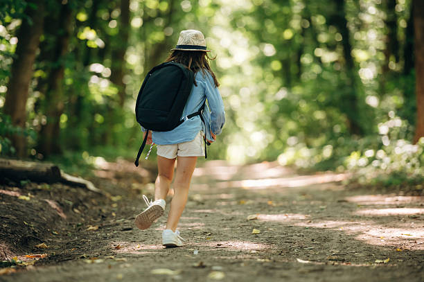 istock In hat and with backpack. Young girl hiker is in the forest 2241411324