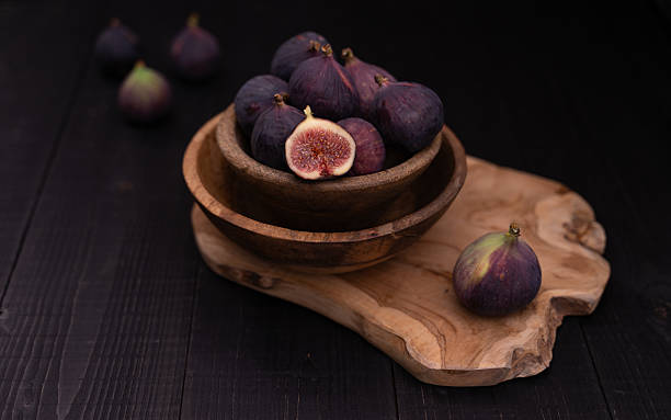 istock Half Sliced Fig in Stacked Wooden Bowls with Whole Fig in Foreground 2241411799