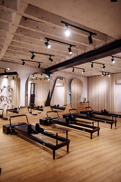 Bright Pilates Studio With Reformers, Mirrors, Track Lighting, and Modern Wooden Floor