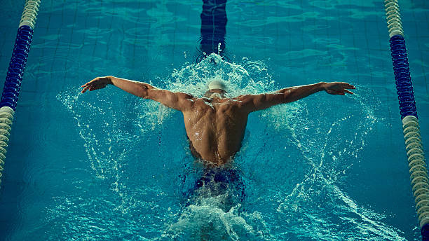 istock Powerful butterfly stroke by male swimmer in competitive pool 2241412999