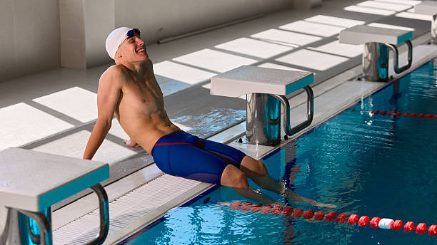 Relaxed Asian man leaning against the edge of a public swimming pool