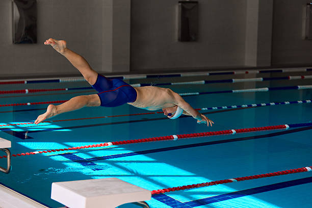 istock Professional swimmer mid air dive over pool lanes 2241413011