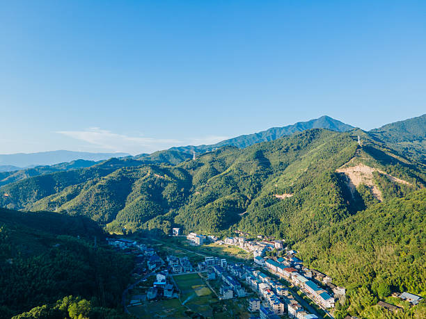 istock Peaceful mountain village surrounded by lush green forests and rolling hills under clear skies, representing quiet rural life, harmony with nature, and sustainable living in a serene environment. 2241415428