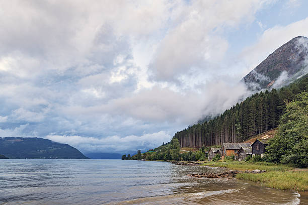 istock Fiord with weathered hytter cabins beneath misted cliffs and dramatic sky 2241416079