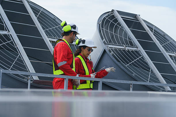 istock Two construction engineers inspect a cooling tower system in an industrial area. They focus on the complex process of dismantling the cooling system as part of a necessary maintenance job. 2241418329