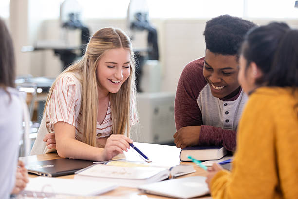 eine bunt gemischte gruppe junger erwachsener, die während einer lernsitzung zusammenarbeiten und lachen - schüler der sekundarstufe stock-fotos und bilder