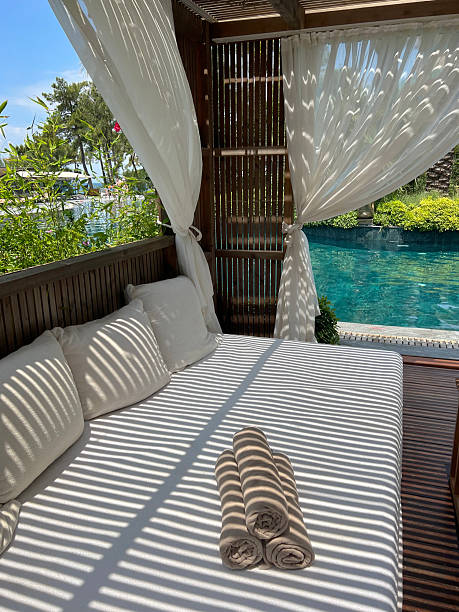 istock Wooden lounger with white curtains and pool view 2241425499