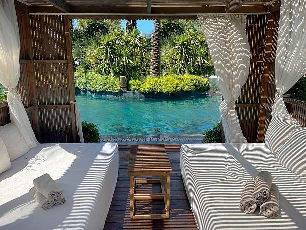 istock Wooden lounger with white curtains and pool view 2241425501
