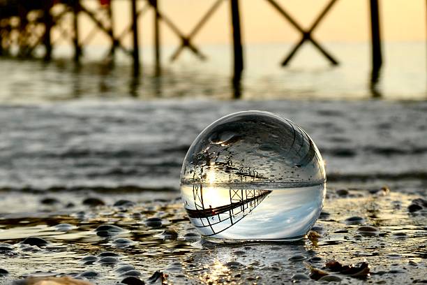 close-up of crystal ball in Rimini beach during dawn with pier in background