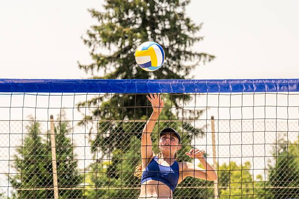 istock Female Volleyball Player Spikes Ball over Net on Beach 2241431353