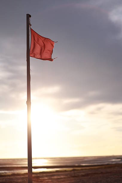 istock Red flag is flying on a pole in the ocean 2241432515