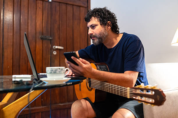 istock Man studying acoustic guitar at home 2241436899