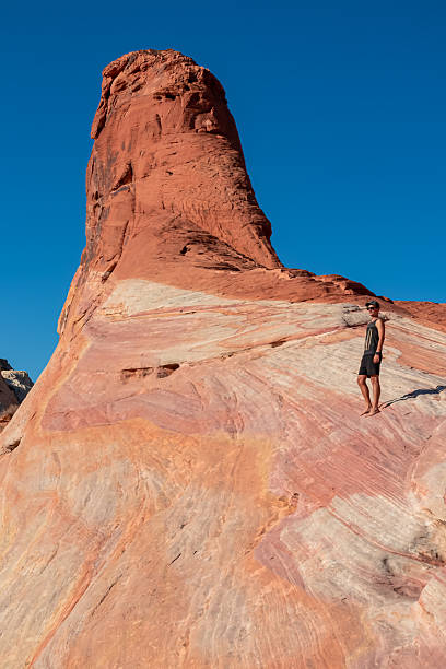 istock Valley of Fire - Man climbing striated red and white rock formations along the White Domes Hiking Trail in Valley, Nevada, USA 2241438546