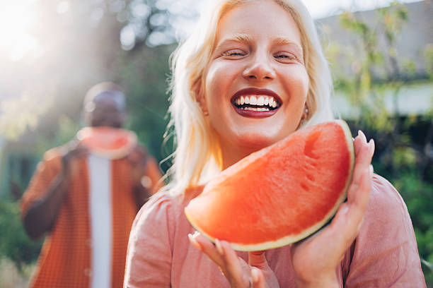 istock Joyful Woman Laughing While Holding Watermelon Slice Outdoors Under Bright Sunlight, Fresh Summer Moment 2241438874