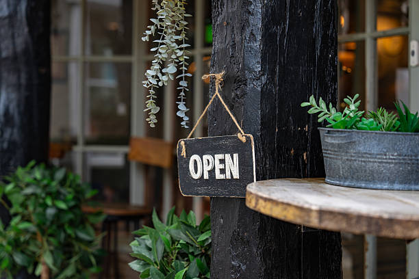 Open sign hanging on a wooden post with plants in dartmouth, devon