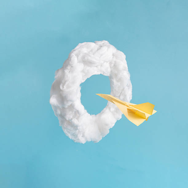 istock A bright yellow paper airplane sails through a fluffy white cloud ring, set against a clean blue backdrop. 2241450460